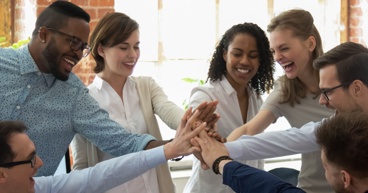 Various employees happily put their hands together in a cheer representing their contentment in the workplace and how this results in great employer branding.